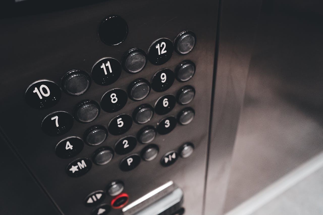 Detail view of a sleek elevator control panel with metallic finish and numbered buttons.